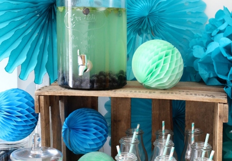 Beim Sweet Table in Aqua-Tönen kommen Papierfächer, Wabenbälle und Pom Poms perfekt zum Einsatz.